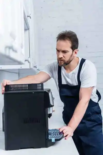 Handyman doing general work, repairing the coffee machine in the kitchen