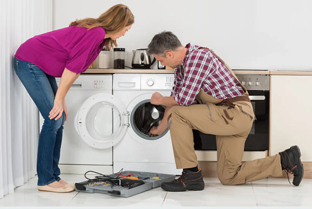 Repairman fixing washing machine with customer