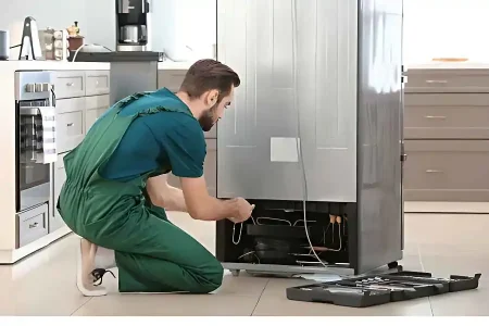 Technician repairing refrigerator in kitchen