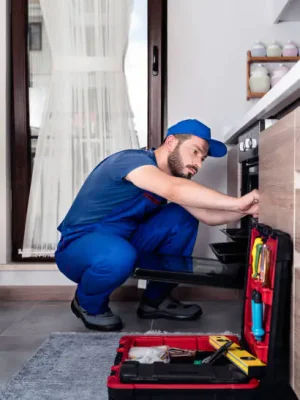 Technician repairing electric oven in home kitchen